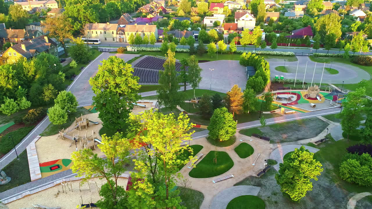 Children's Playground Area Surrounded by Trees in Warm Sunlight, Aerial Orbital Drone Shot