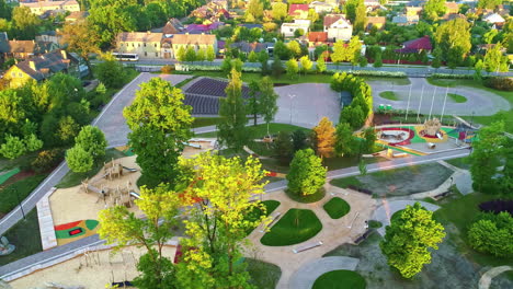 children's playground area surrounded by trees in warm sunlight, aerial orbital drone shot