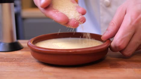 el cocinero espolvorea azúcar en el budín