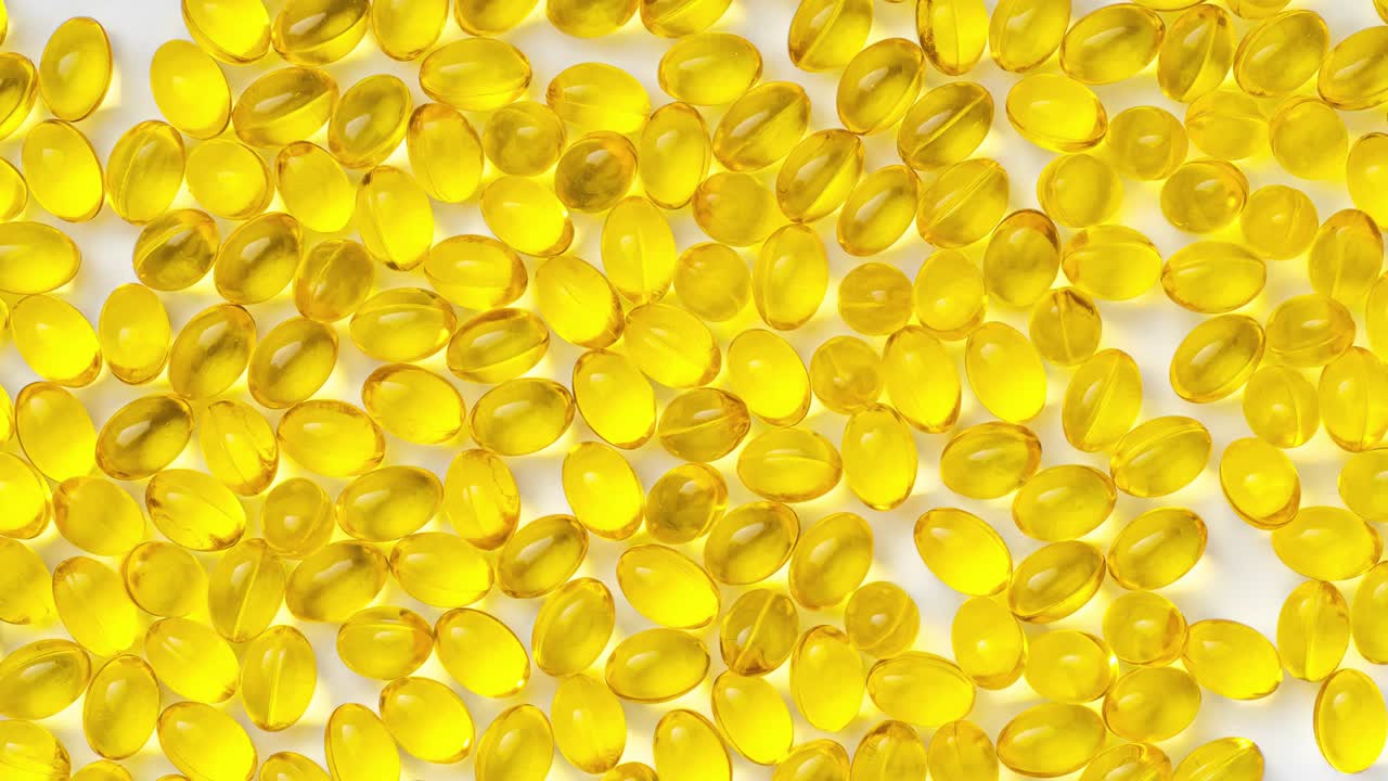 pastillas transparentes amarillas sobre un fondo blanco, video de movimiento de parada. pastillas con vitamina d3.