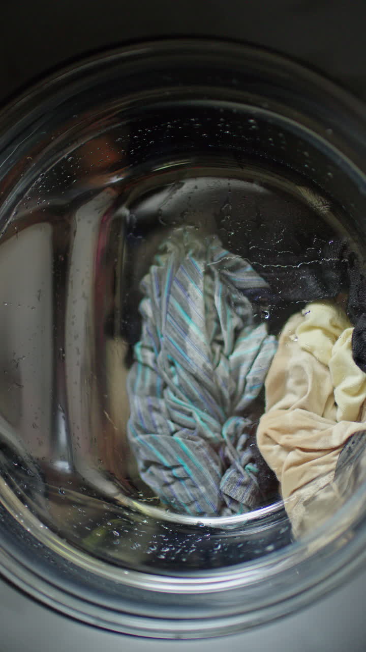 Laundry spinning inside front load washing machine during wash cycle at home
