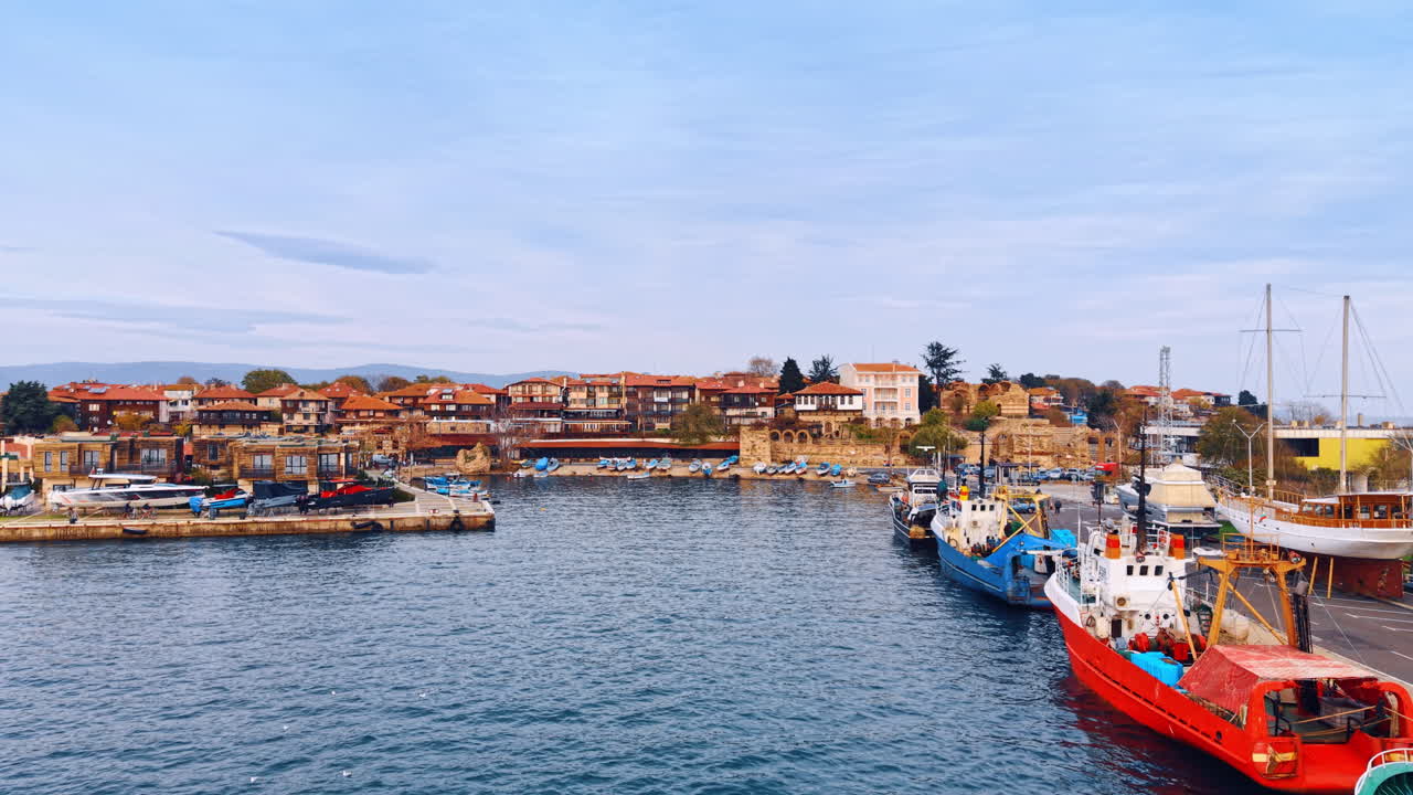 Flygning längs piren med fiskebåtar vid kajen. Måsar flyger över vattenlandskapet. Närmar sig stadsbilden vid Svartahavskusten.