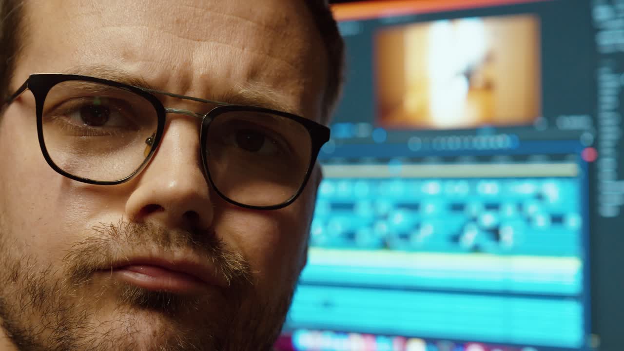 Close-up of a frustrated man sitting in front of video editing software, showing disappointment and creative burnout. Concept of stress, error, or software problem