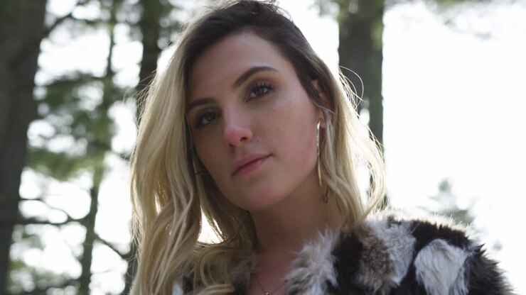 confiante jeune femme blonde pose pour la caméra dans un décor de forêt d'hiver