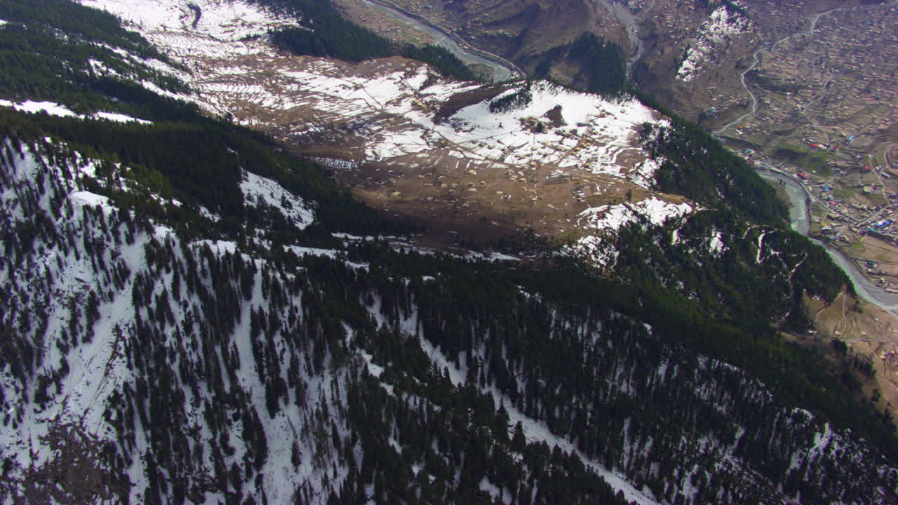 vista aérea sobre el valle con casas coloridas, estilo de vida y río que crean una vista pintoresca de las montañas cubiertas de nieve y bosques de pinos.