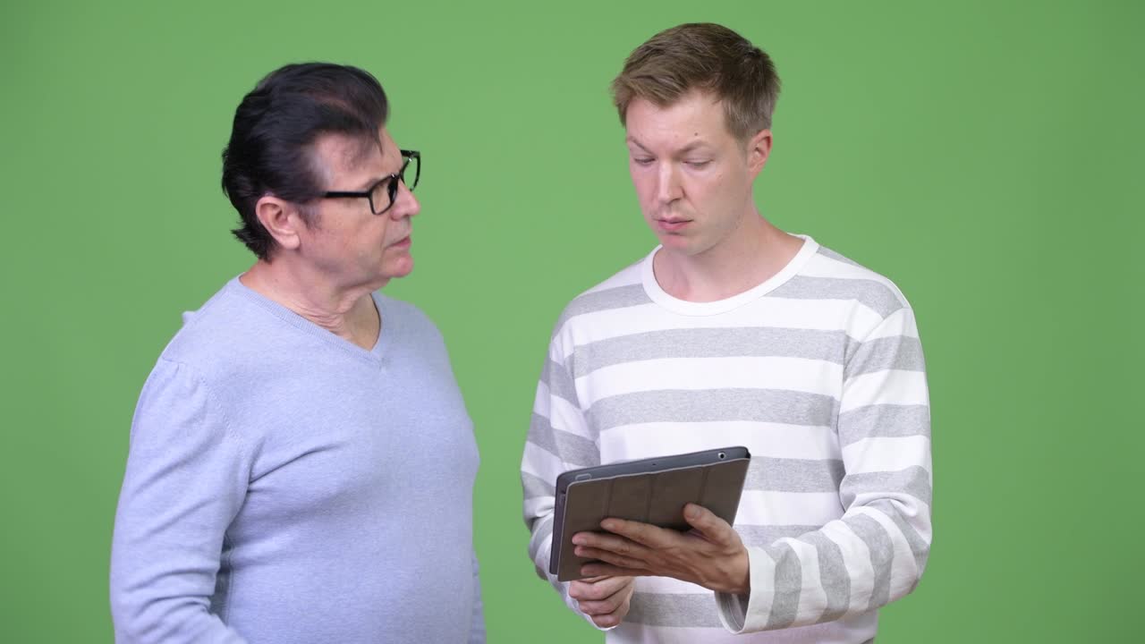 hombre guapo anciano y hombre guapo joven usando tableta digital juntos
