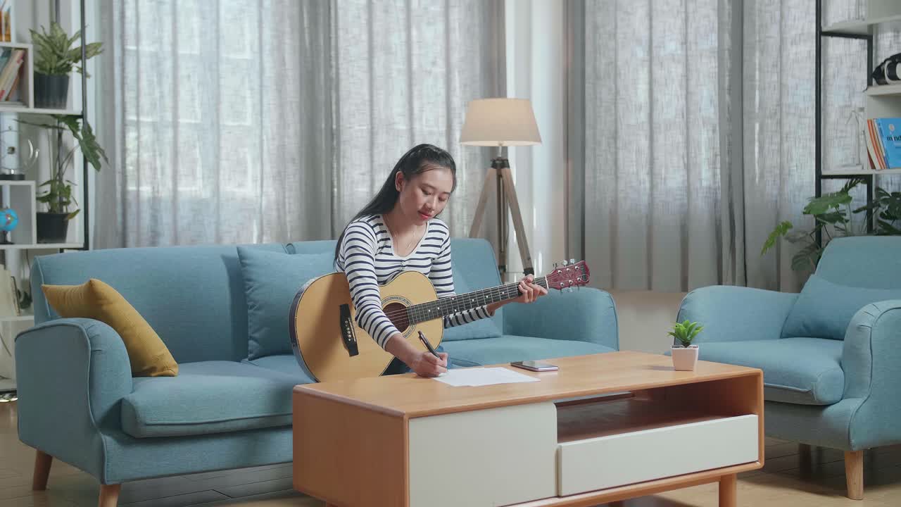 거실 의 소파 에서 노래 를 연주 하고 작곡 하는 여자