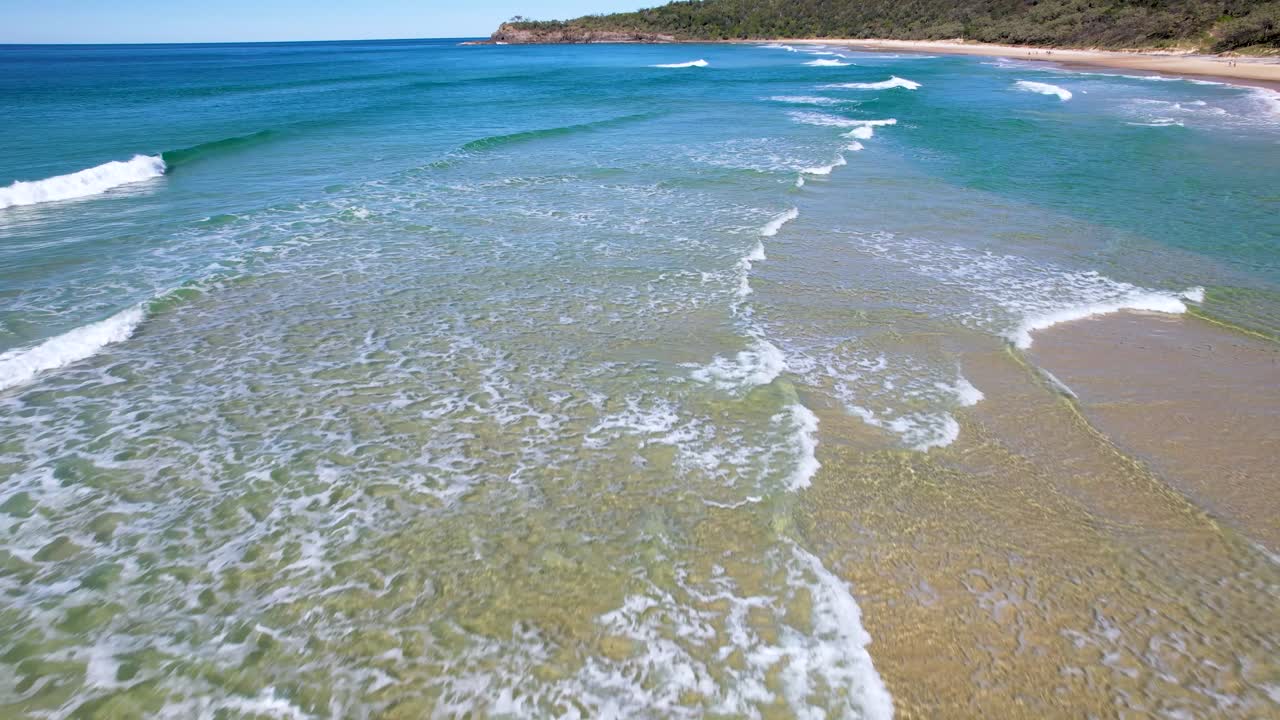 video de dron de 4k volando hacia adelante sobre las olas del océano azul estrellándose hacia la playa de arena blanca en noosa, queensland, australia