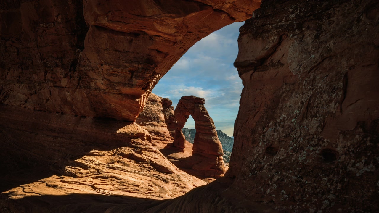 Video in loop del Delicate Arch incorniciato da un cielo nuvoloso. Paesaggio dell'Arches National Park, Utah, USA. Time lapse