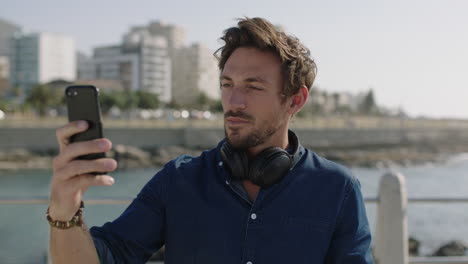 retrato de un joven atractivo usando un teléfono inteligente tomando fotos en la hermosa playa costera