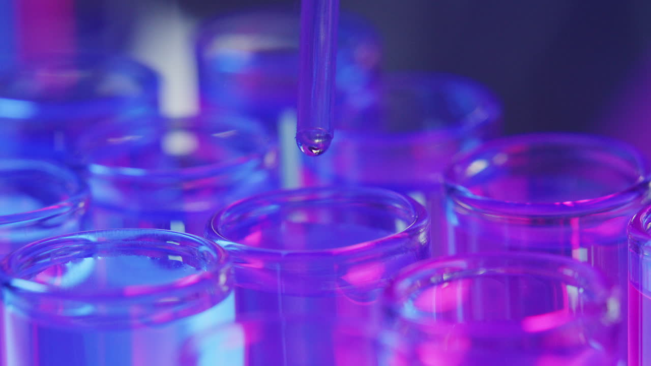 Dropping Fluid Sample into Test Tube under Vibrant Neon Light in Laboratory