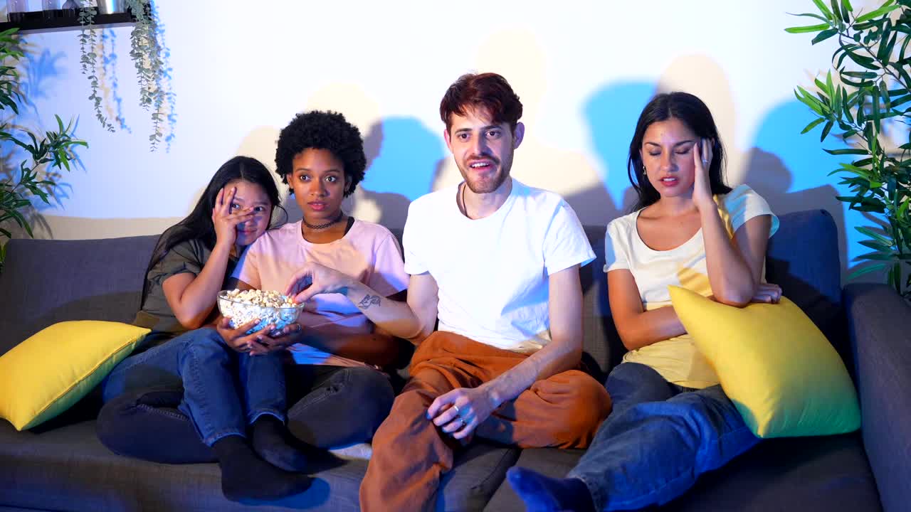 Friends watching a scary movie with popcorn