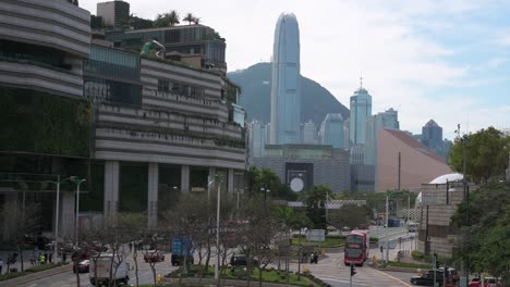 vehicles drive and travel along a road as the hong kong island skyscrapers and financial district is seen in the background