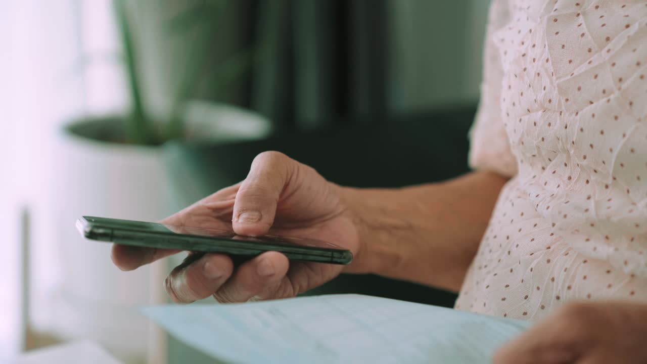 una anciana asiática tiene varias facturas de gastos y planes para las finanzas personales en la sala de estar de su casa.