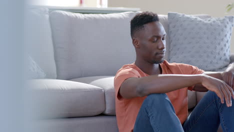 Worried-african-american-man-sitting-and-thinking-in-sunny-living-room,-slow-motion