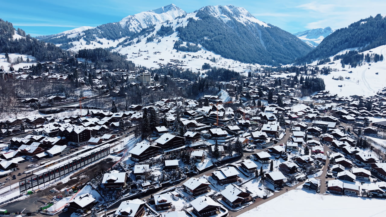 Aerial: Gstaad snowy cityscape during the day in Canton of Bern, Switzerland, orbit drone shot