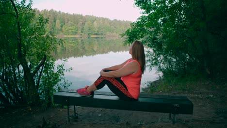 una mujer caucásica con ropa deportiva sentada en un banco del parque y relajándose
