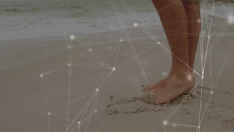 network of connections against low section of a man standing at the beach