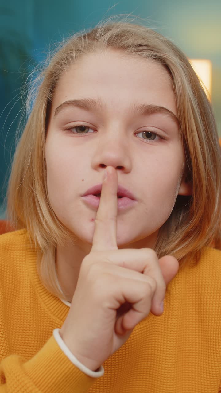 Ragazzo adolescente che porta il dito alle labbra, facendo segno di silenzio, per non rivelare pettegolezzi o segreti