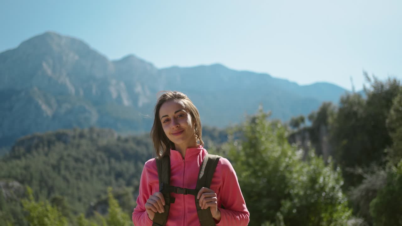 4k cinematográfico en primer plano en cámara lenta de una mujer sonriente caminante de pie en un hermoso paisaje de montaña, chica feliz con el cabello soplando en el viento caminando al aire libre en un día soleado, aventura estilo de vida al aire libre