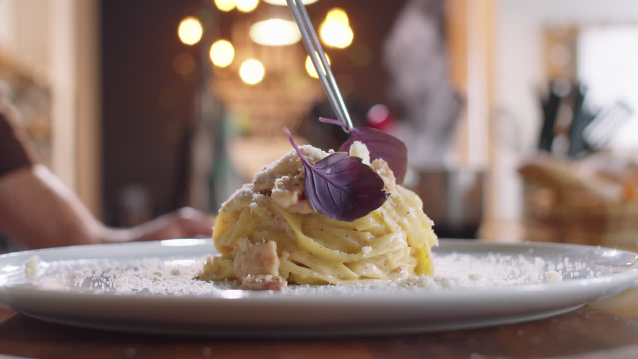 뜨거운 카보나라 파스타에 신선한 바실리 잎을 첨가하는 것