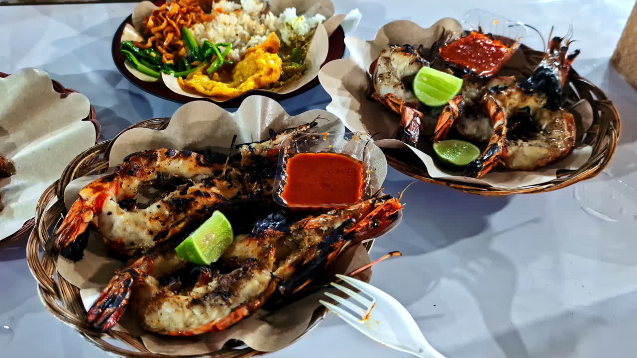 Delicious fresh-grilled king prawns and shrimp served with spicy sambal chili sauce and lime at a night food market on the tropical island of Gili Trawangan, Indonesia