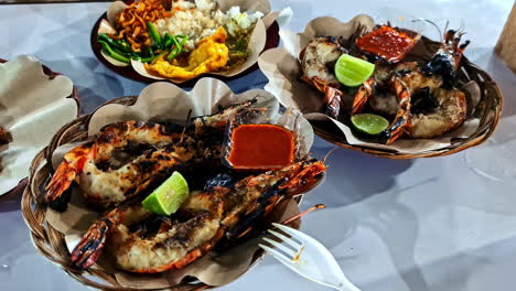 delicious fresh-grilled king prawns and shrimp served with spicy sambal chili sauce and lime at a night food market on the tropical island of gili trawangan, indonesia