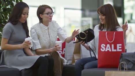 mujer mostrando la bolsa del hombro a sus amigos