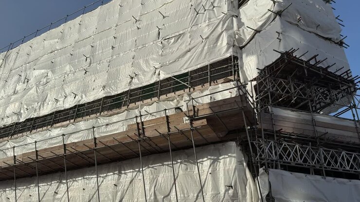 Edificio in ristrutturazione avvolto in telo protettivo bianco.