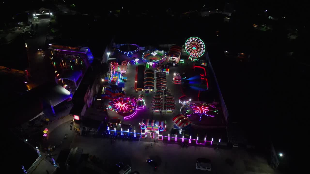 Aerial orbit of bustling amusement park, attractions and neon lights during night time - Virac, Catanduanes, Philippines