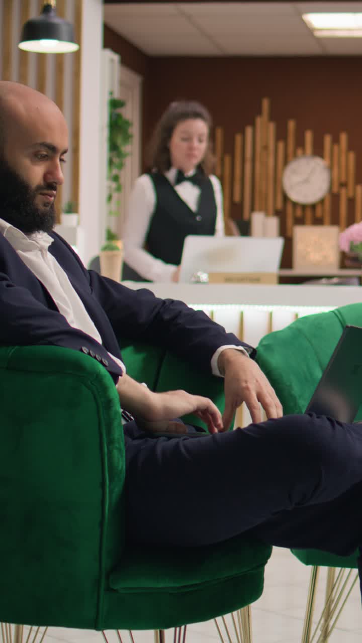 Investitore in video verticali che esamina appunti su un laptop in hotel