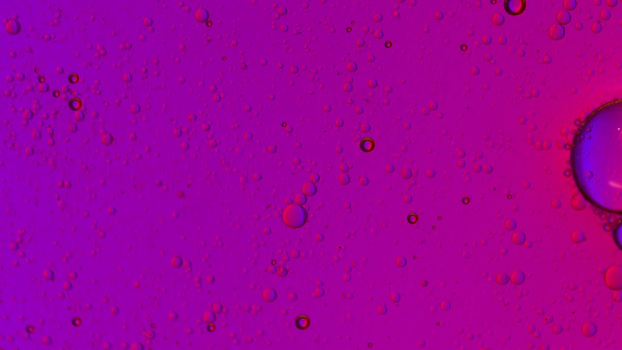 grandes burbujas de aire flotan en un líquido grasiento rosa y azul
