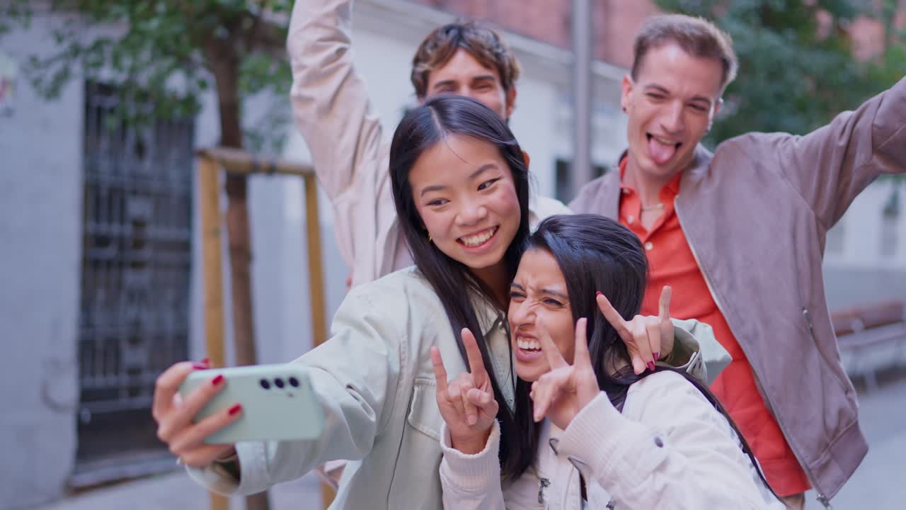 Amici multietnici felici che si fanno dei selfie in strada