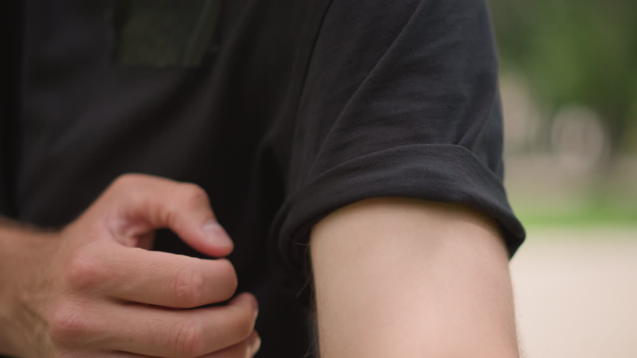 Person Prepares With Smooth Sleeve Movement, Relaxed Individual Adjusts Clothing Calmly On Sunny Day, Person Gently Rolling Up Their Sleeve In Peaceful Outdoor Setting Under Bright Sunlight