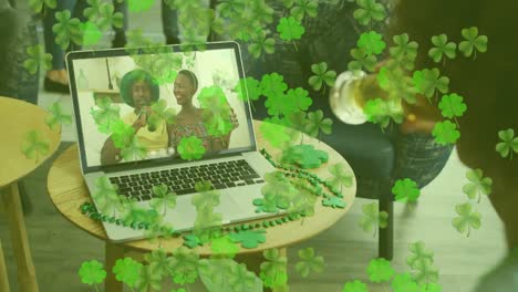 Animation-of-clover-leaves-falling-over-man-celebrating-with-friends-on-laptop-video-call