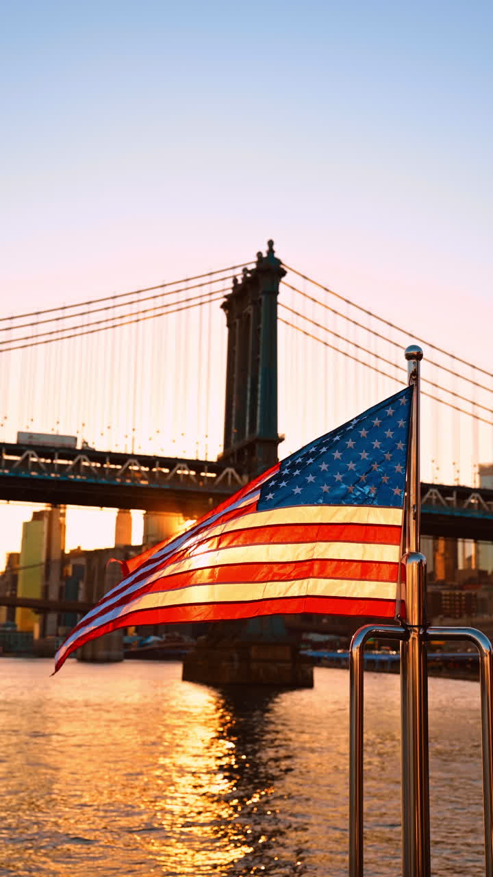 Albero di una barca con bandiera americana al vento al tramonto. Visuale dal basso che inquadra il Manhattan Bridge sullo sfondo. Video verticale