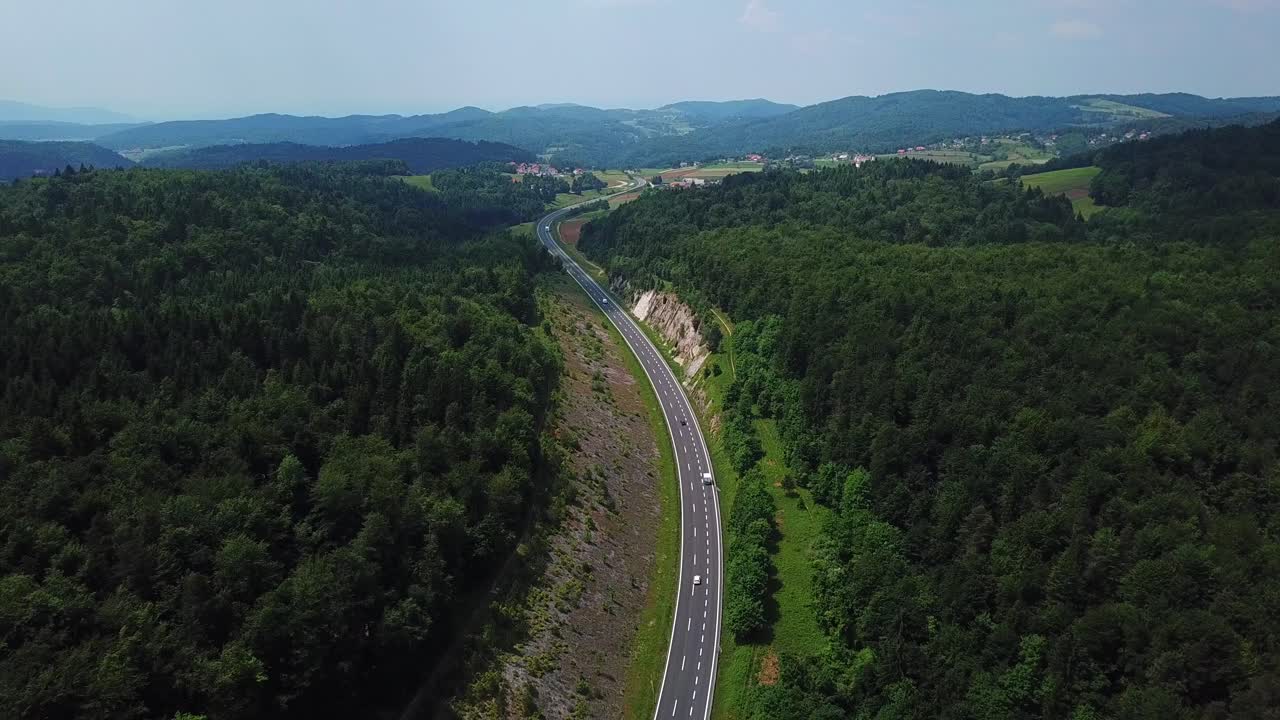 vista aérea de una carretera de montaña rodeada por un bosque verde