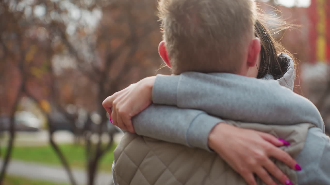 Romantic moment of two lovers embracing affectionately outdoors while gazing into each other eyes, standing close with warm smiles as they share connection and intimacy surrounded by autumn scenery