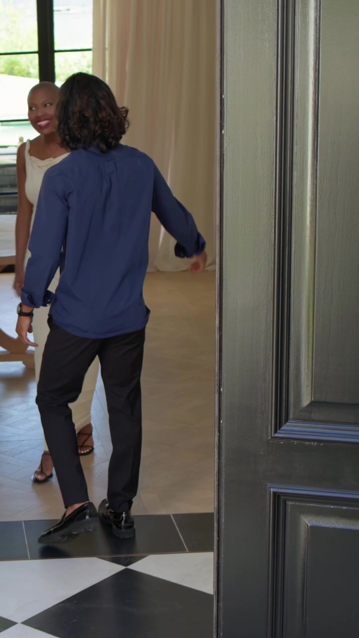 Vertical video: Opening door, man in blue shirt greeting hosts at foyer, door handle closing