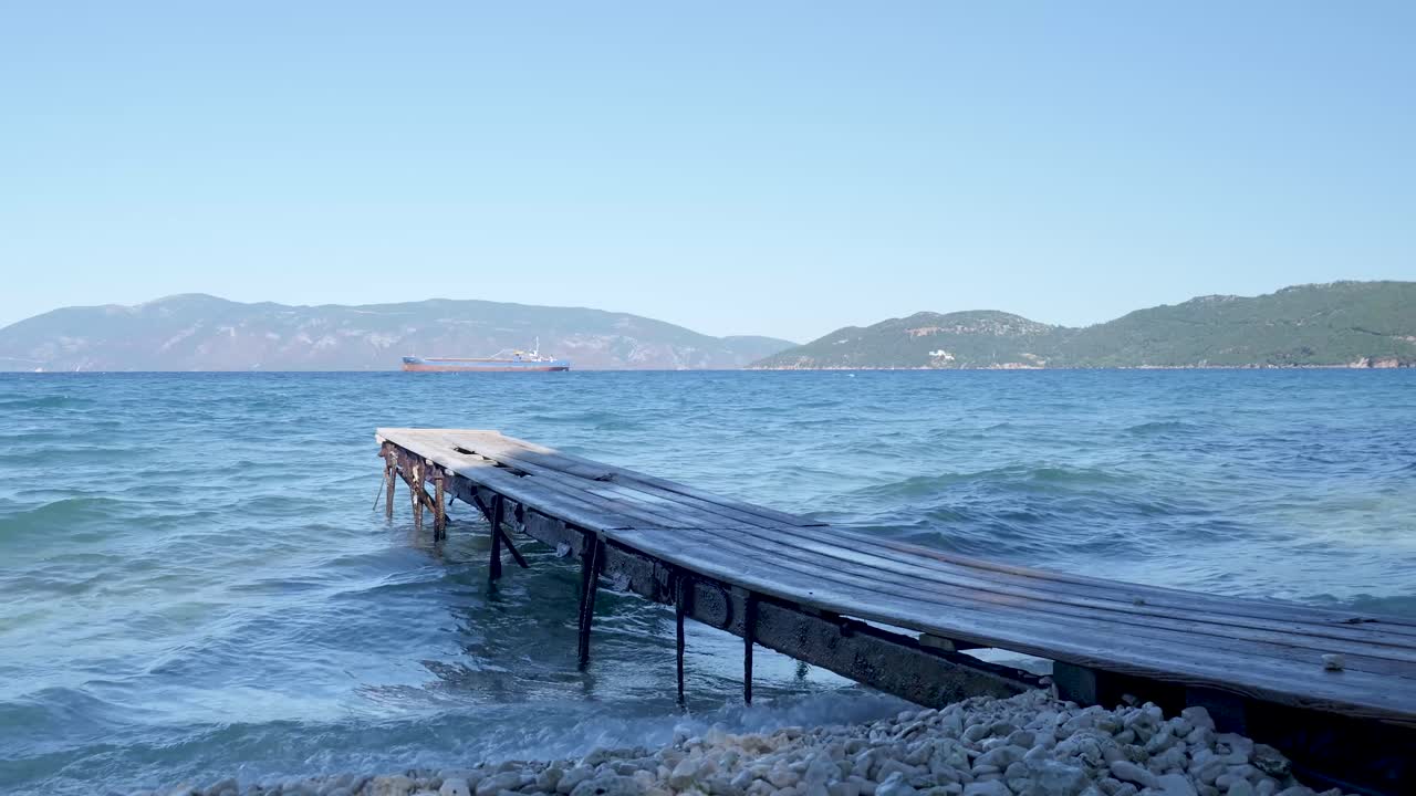 Wooden Pier on a Calm Beach with a Ship in the Distance