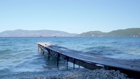 wooden pier on a calm beach with a ship in the distance