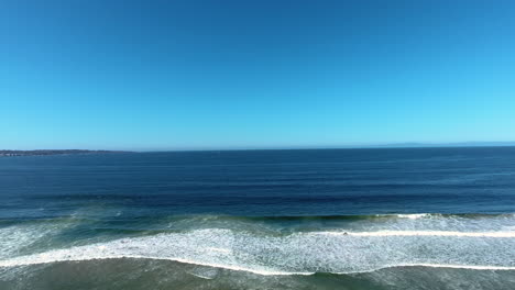 aerial drone view of ocean with waves crashing and sand in monterey california shot in 4k high resolution