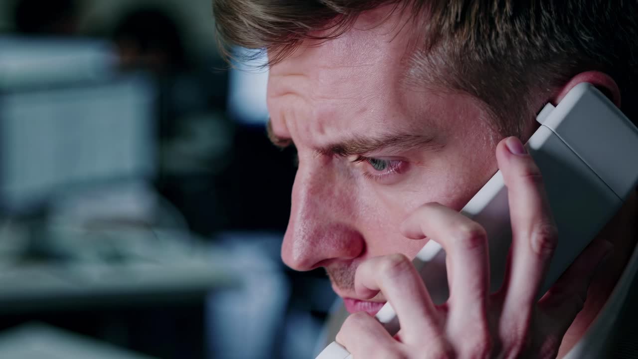 Close-up shot of a man on the phone, focused and serious. The side angle captures his expression