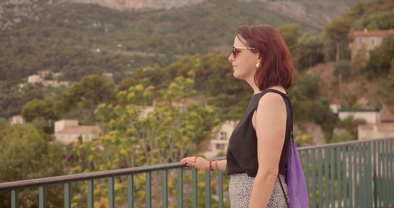 Woman enjoying a scenic view over the French Riviera, South of France. Relaxed tourist standing on a balcony overlooking the Mediterranean landscape, summer travel lifestyle and vacation vibes.