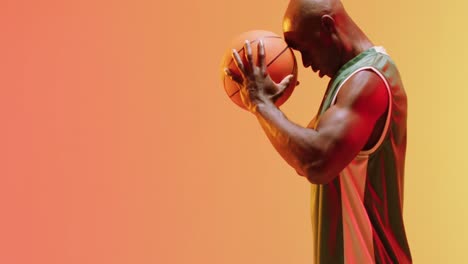 video of african american male basketball player holding ball on orange background