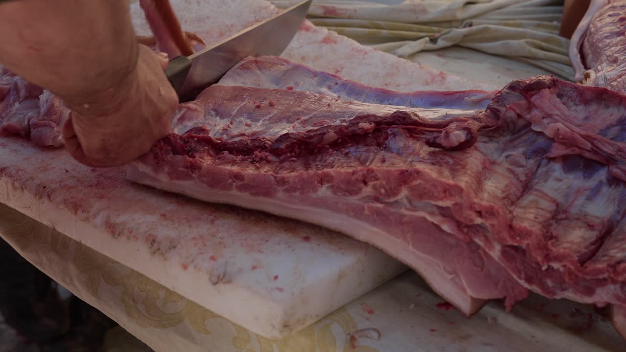 Man cutting pork ribs on table during traditional butchering in rural Portugal
