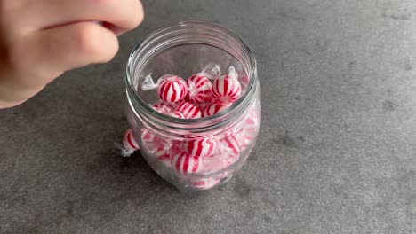 kid hand takes candy out of a glass jar and then takes entire jar