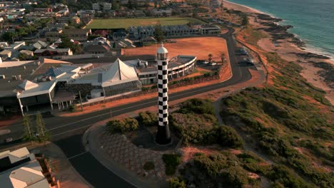 Bunbury-Lighthouse-In-Australia-At-Sunset,-Overlooking-Coastal-Neighborhoods,-Aerial-Orbital-View