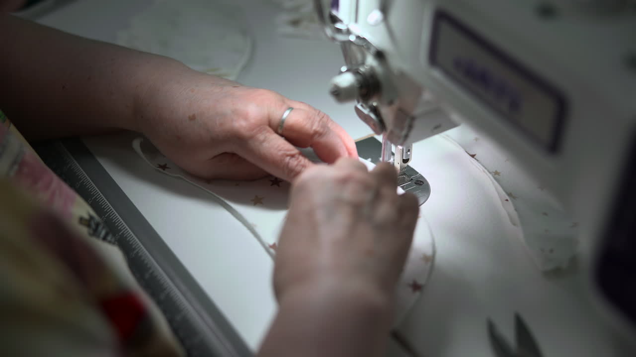 White Dressmaker Handfinishing Childs Garment On Sewing Machine, Closeup Hands Smoothing Soft Cotton Print. Media