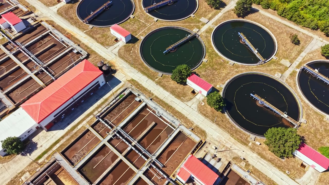Water treatment facility operates in a planned layout with several tanks and buildings visible from above on a bright day